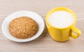 One cookie in saucer and yellow cup of milk Royalty Free Stock Photo