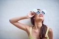 She is one cool chick. Studio shot of a cheerful young woman wearing sunglasses while posing against a grey background.