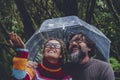 One couple have fun and enjoy bad weather rain under a transparent umbrella smiling together and checking drops water. Outdoor Royalty Free Stock Photo