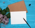 One Craft envelop, white paper, brunch of lilac, candle on vintage turquoise wooden background