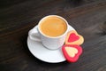 One cup of hot coffee with a pair of heart shaped cookies on dark color wooden table Royalty Free Stock Photo