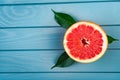 One cut grapefruit with green leaves lies on a blue wooden table. view from above Royalty Free Stock Photo