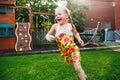 One cute adorable Caucasian blonde little wet messy girl running on backyard Royalty Free Stock Photo