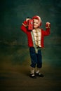 One cute little boy dressed up as medieval little prince and pageboy having fun over dark vintage style background