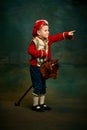 One cute little boy dressed up as medieval little prince and pageboy ride toy horse over dark vintage style background