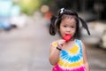 One cute little child girl eating red Popsicle sticks. Asian children stroll in the summer evening.