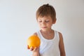 One cute smiling healthy little caucasian kid holding fresh orange in hand on bright white background Royalty Free Stock Photo