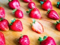 One cutted strawberry in an srranged pattern of strawberries on