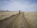 One cyclist in bright clothes rides on the field road among the endless steppes in spring