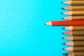 One different pencil standing out from others on color background, top view. Royalty Free Stock Photo