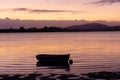 One dinghy in silhouette moored in bay with surface ripples at sunrise