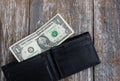 One dollar is lying in an empty leather wallet. No money in the purse. Poverty and unemployment. Old wooden rustic background Royalty Free Stock Photo