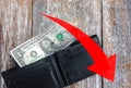 One dollar is lying in an empty leather wallet. Red arrow going down. Currency rate falling. Economic crisis. No money in the Royalty Free Stock Photo