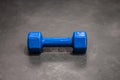 Dumbbell in a silicone shell of blue color on the gray floor