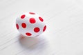 One Easter egg with red points on white wooden background Royalty Free Stock Photo