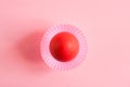 One Easter red egg in pink cupcakes mold in the middle of a pink background with copy space. Top view. Royalty Free Stock Photo