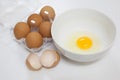 One egg yolk in white bowl and broken egg shells