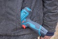 one electric screwdriver lies in the pocket of a gray jacket on a worker