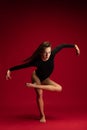 One emotional young flexible contemp dancer, ballerina jumping on dark red background. Art, beauty, inspiration