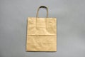 One empty brown shopping bag with handles on gray background with copy space. Recycled paper bag. Mockup for design. Royalty Free Stock Photo