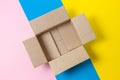 One empty open cardboard box on geometric pink, blue, yellow background. Top view Royalty Free Stock Photo