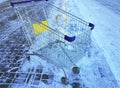 One empty shopping cart stands outdoors in winter on snow, supermarket cart Royalty Free Stock Photo