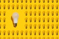 One energy saving white lamp and many incandescent lamps on a yellow background. Idea concept Royalty Free Stock Photo
