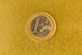 One Euro coin on the yellow shiny metal background