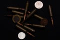 One euro, one Russian ruble and Ukrainian hryvna coins with rifle military ammo on black background. Symbolizes war for money- big