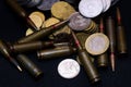 One euro, Russian ruble and small Ukrainian coins with rifle military ammo on black background. Symbolizes war for money