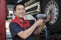 An Asian male auto technician is changing car wheel at service garage. Royalty Free Stock Photo