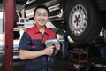 An Asian male auto technician is changing car wheel at service garage. Royalty Free Stock Photo