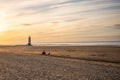 One family sat all alone together on deserted big clean beach vacation watching sunset with lighthouse and golden hour beautiful Royalty Free Stock Photo