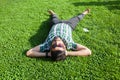 One fashion middle eastern man with beard, fashion hair style is resting on beautiful green grass day time. Royalty Free Stock Photo