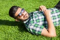 One fashion middle eastern man with beard, fashion hair style is resting on beautiful green grass day time. Royalty Free Stock Photo