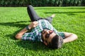 One fashion middle eastern man with beard, fashion hair style is resting on beautiful green grass day time. Royalty Free Stock Photo