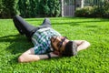 One fashion middle eastern man with beard, fashion hair style is resting on beautiful green grass day time. Royalty Free Stock Photo