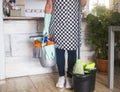 One female people ready to start with the housework. Close to she a plastic bucket with items for cleaning. One alone people with