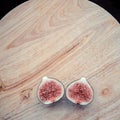 One fig sliced in half on on wooden board background. Focus is on the sliced fig Royalty Free Stock Photo