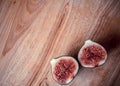 One fig sliced in half on on wooden board background. Focus is on the sliced fig Royalty Free Stock Photo