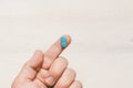 One Finger Holding A Blue Pill On White Wooden Background Royalty Free Stock Photo