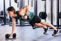 One fit young caucasian man doing renegade rows in plank position on the ground with dumbbells while training in a gym Royalty Free Stock Photo