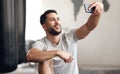 One fit young hispanic man using a cellphone to take selfies while on a break from exercise in a gym. Happy mixed race Royalty Free Stock Photo