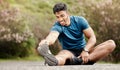 One fit young indian man touching his feet and stretching legs for warmup to prevent injury while exercising outdoors Royalty Free Stock Photo