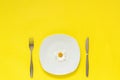 One flower chamomile daisy on plate, cutlery fork knife on yellow paper background Concept vegetarian healthy eating diet or Royalty Free Stock Photo