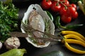 Fresh raw dorada fish in a white dish with a set of vegetables on a black table Royalty Free Stock Photo