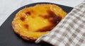 One freshly baked Pastel de nata or Portuguese egg tart in a baking dish. Pastel de Belm is a small pie with a crispy