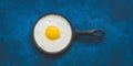 One fried egg in a pan on a blue painted background, banner. Scrambled egg, border. Top view, flat lay, toned photo