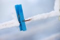 One frozen blue wooden peg covered in snow on a line. An old wooden clothespin on a washing line in an icy garden. Old Royalty Free Stock Photo