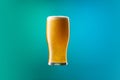 One full glass of frothy light beer isolated over gradient blue and green color background in neon. Concept of alcohol